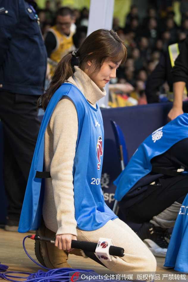 工作间隙，美女主持手拿纸质资料，倚靠在通道墙边，简单随性的姿势难掩其温婉气质，仿佛在思考下一节如何调动现场气氛。