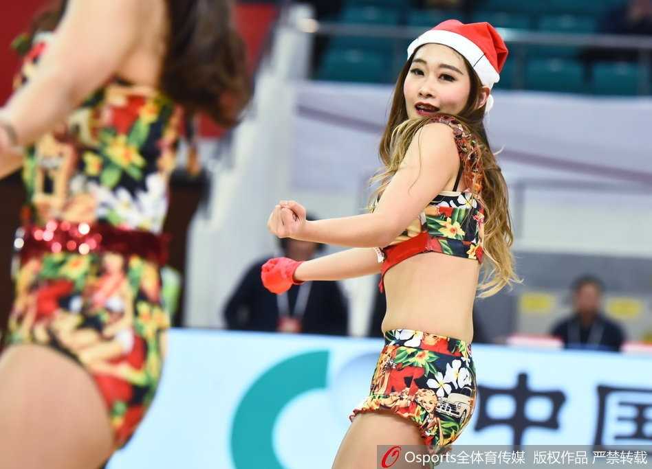 一位篮球宝贝手持彩球，头戴圣诞鹿角，在赛场边露出甜美微笑。