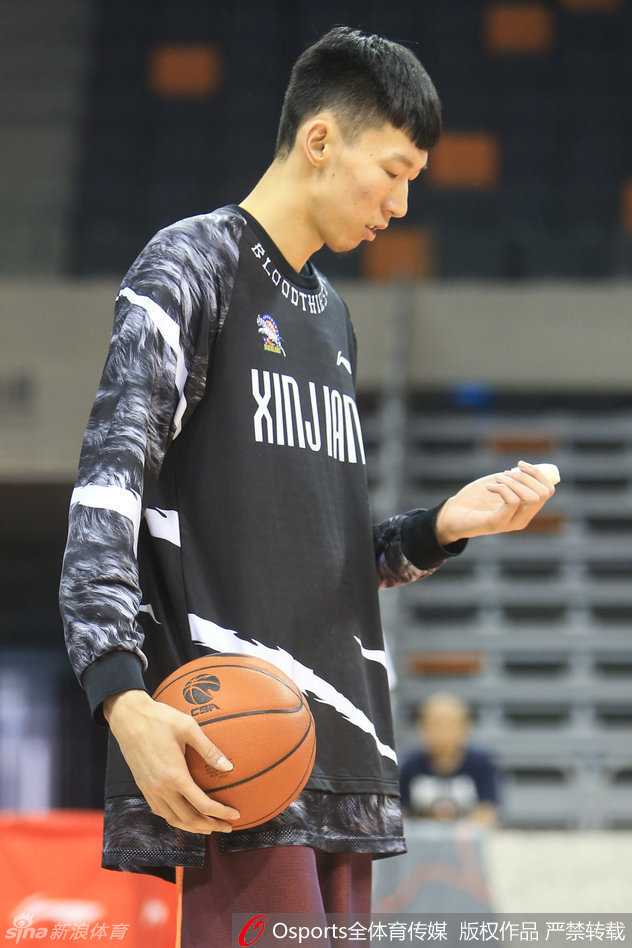 周琦在场上进行投篮训练，他高高跃起单手投篮，左手拇指被白色绷带牢牢固定，与黑色的护具形成鲜明对比