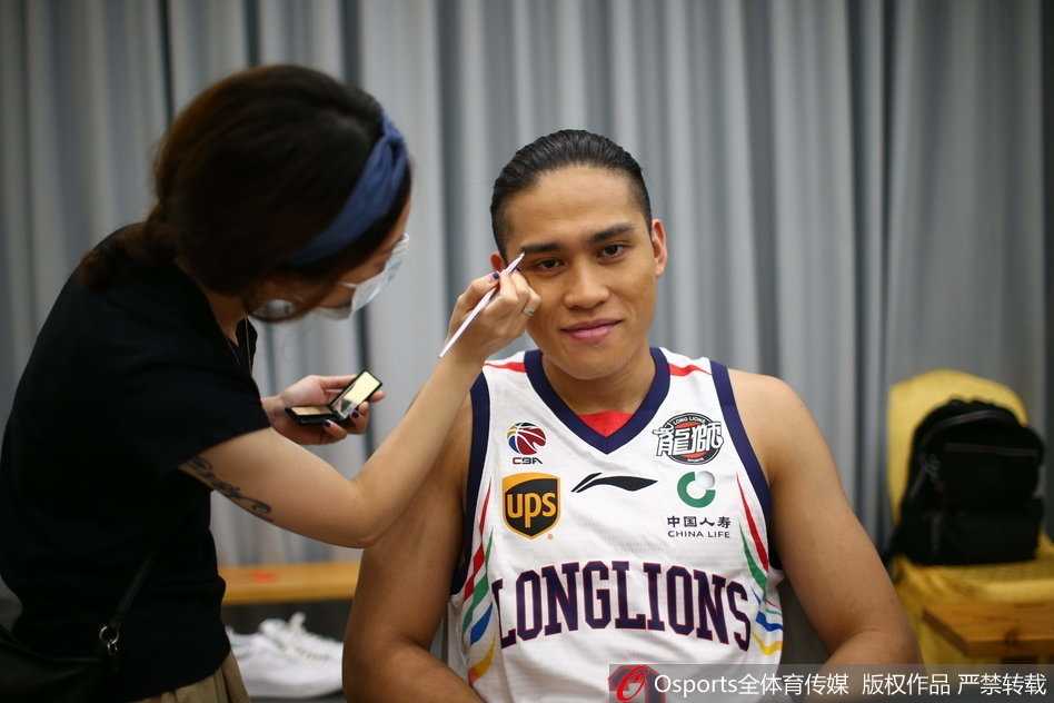 状元郎陈盈骏端坐在化妆镜前，化妆师为他打理发型，灯光下的每一根发丝都在诉说着一个新赛季、一个新希望在广州龙狮悄然萌芽。