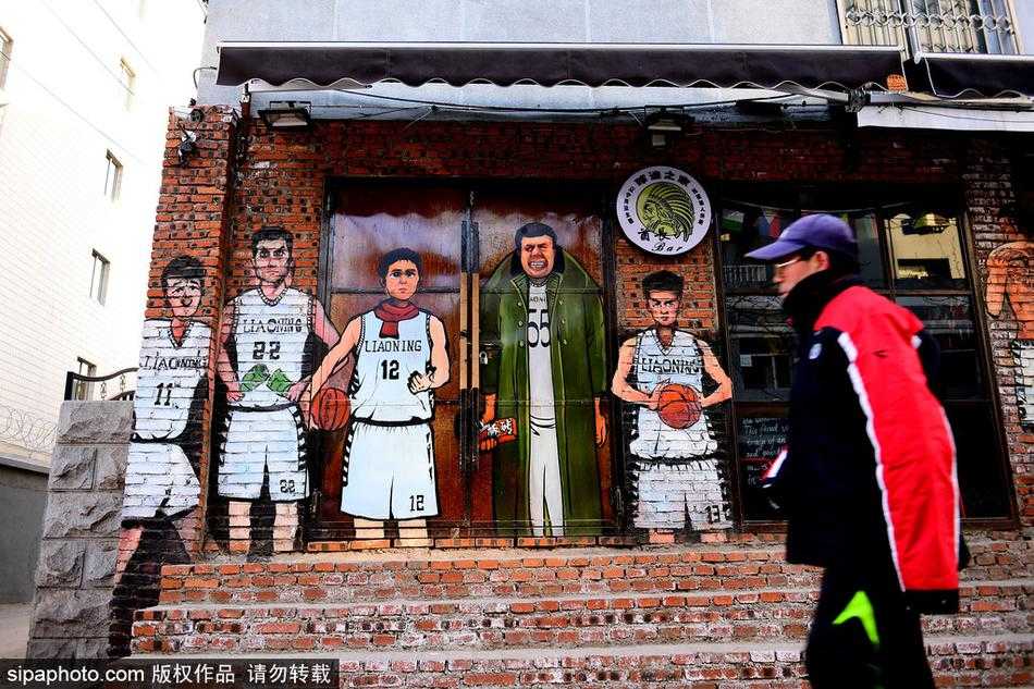 沈阳街头，巨幅漫画墙前，身披军大衣的韩德君如同一位扛着板砖的球场老大爷，眼神里写满了“谁与争锋”的霸气。