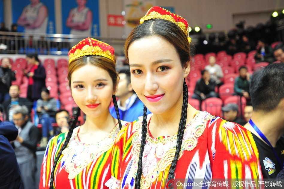 新疆主场惊现西域风华 异域之美点燃冬日激情 一位拥有深邃眼眸的新疆美女,她身着盛装,在主场灯光的照耀下微笑,精致的五官如同雕刻般立体,瞬间成为全场焦点。