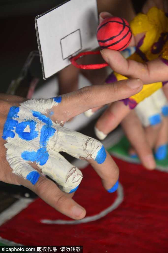 一位学生正全神贯注地盯着指尖下的‘篮球赛场’，他微微弯下腰，用涂了颜色的手指灵活地‘运球’突破，脸上的表情既认真又带着忍俊不禁的笑意，仿佛正在进行一场真正的NBA总决赛。