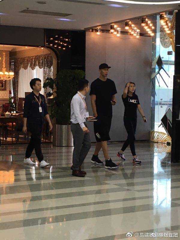 易建联身穿深色休闲装，头戴棒球帽，与身着简约白色上衣的妻子荆灵并肩走在街头，两人都戴着墨镜，神情放松，步伐默契，仿佛自带一种屏蔽喧嚣的宁静气场。