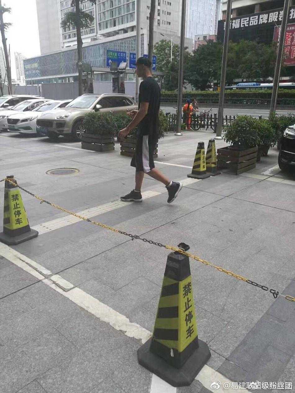 两人行走间自然地靠近彼此，荆灵侧头似在与阿联轻声交谈，阿联则微微侧耳倾听，举手投足间流露出无需言语的信任与亲昵，背景繁华的街景此刻也成了他们二人世界的温馨陪衬。