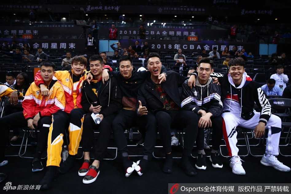 星锐革新夜,巨星助威时:二零一八CBA全明星周末燃情鹏城 丁彦雨航与身旁的队友在观赛间隙神情放松地交谈,身后是座无虚席的深圳球迷,现场气氛热烈而轻松。