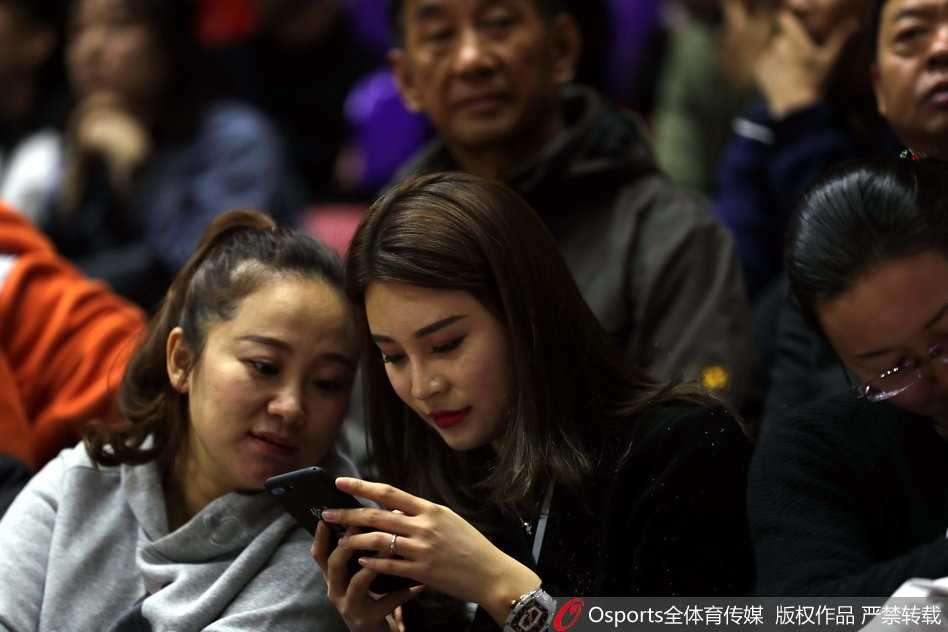 李根妻子与友人现场热聊，眉飞色舞间流露出俏皮的一面，似乎对比赛结果胸有成竹。