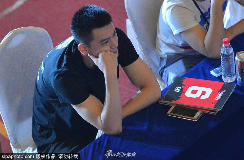 杨鸣与现场的小球员们互动，他微微弯下腰，亲切地拍着一位小球员的肩膀，眼神中满是鼓励与期许，画面温馨而充满传承的意味。