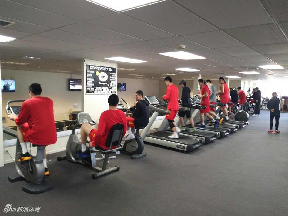 后卫刘晓宇在力量训练中表情刚毅，专注进行上肢力量推举，汗水浸湿了训练服，眼神中透露出坚定的意志。