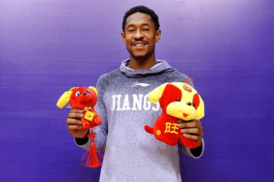 主教练贝西诺维奇面带慈祥笑容，与全体队员合影，背景板上的新春元素和队员们手中的福字，将这个大家庭的温馨时刻永远定格。