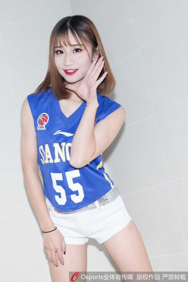 更衣室内，一名KDancer成员手持彩球对镜自拍，镜中映出她俏皮的表情和充满活力的身影，满墙的球队海报成为背景，诉说着她与球队密不可分的联结。