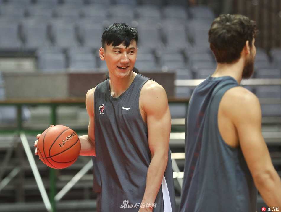 主教练刘维伟手拿战术板在球员中间画线讲解，神情严肃认真，身后年轻球员们聚精会神倾听。