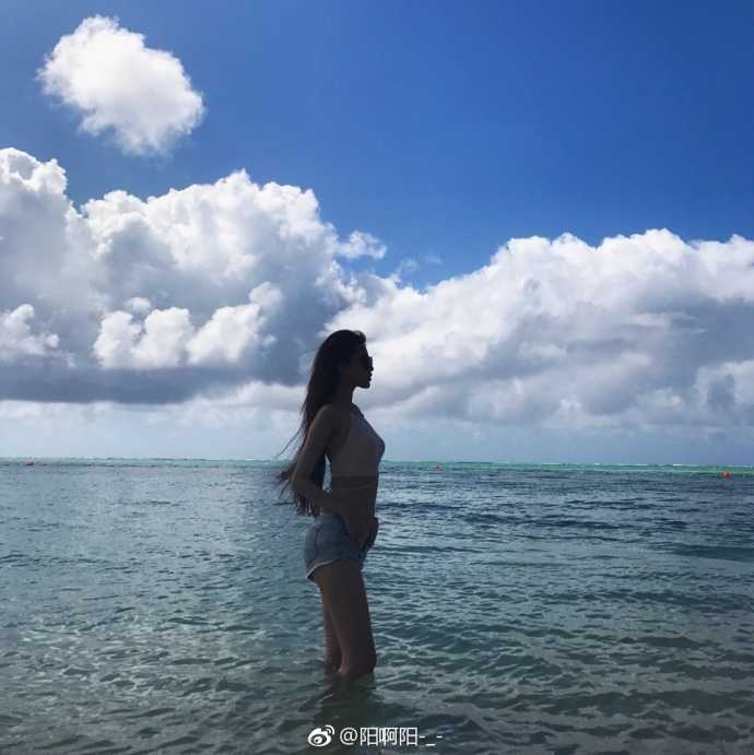 海边的礁石上，马阳阳安静地坐着眺望远方，长发被海风吹起，眼神中带着一丝淡淡的慵懒与温柔，与身后的海天一色融为一体。