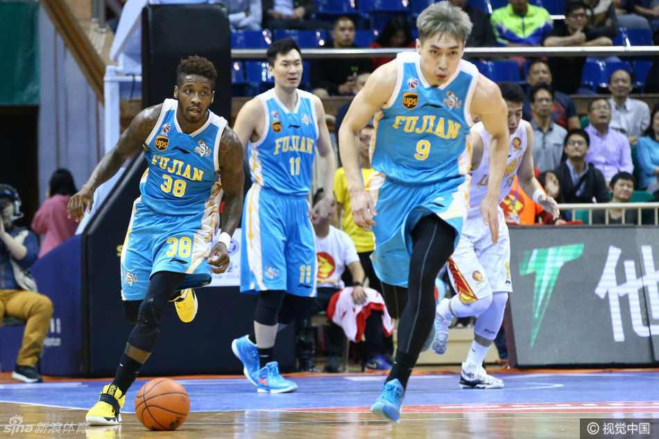 福建队核心王哲林在深圳队内线兰佩与张凯的双人包夹下，失去身体平衡，但仍奋力将球抛向篮筐。