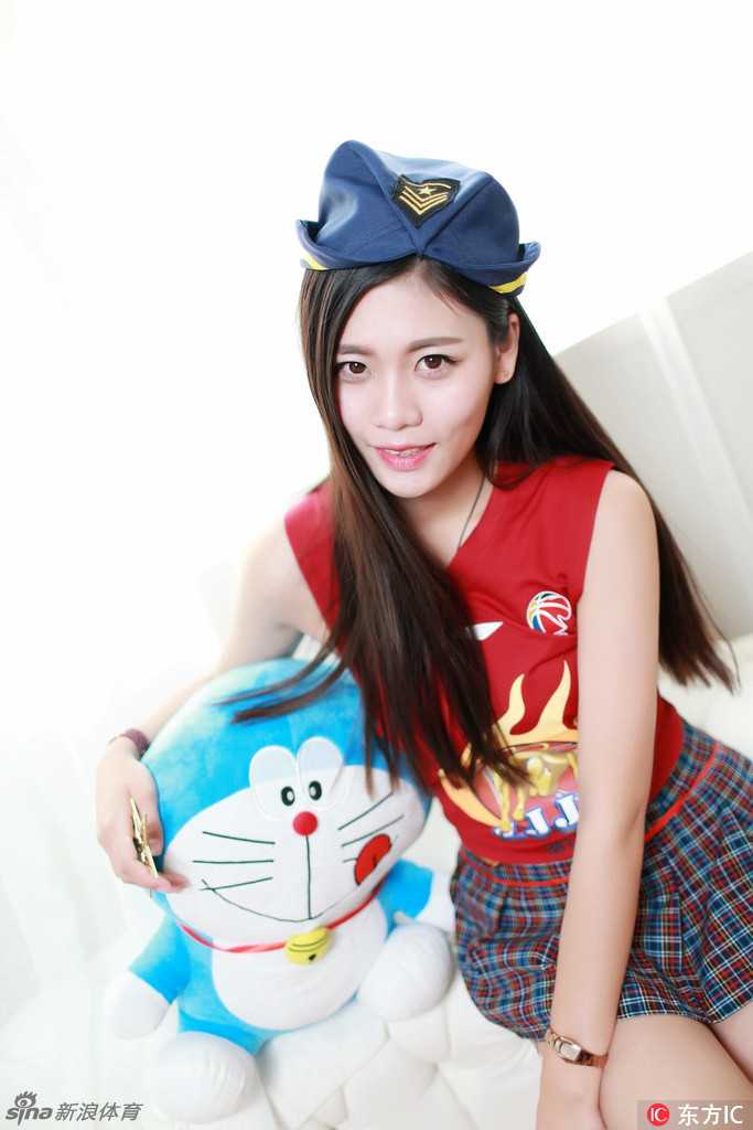 篮球宝贝坐在地上，将玩偶亲昵地贴在脸颊，歪着头露出甜美的梨涡，俏皮模样惹人怜爱