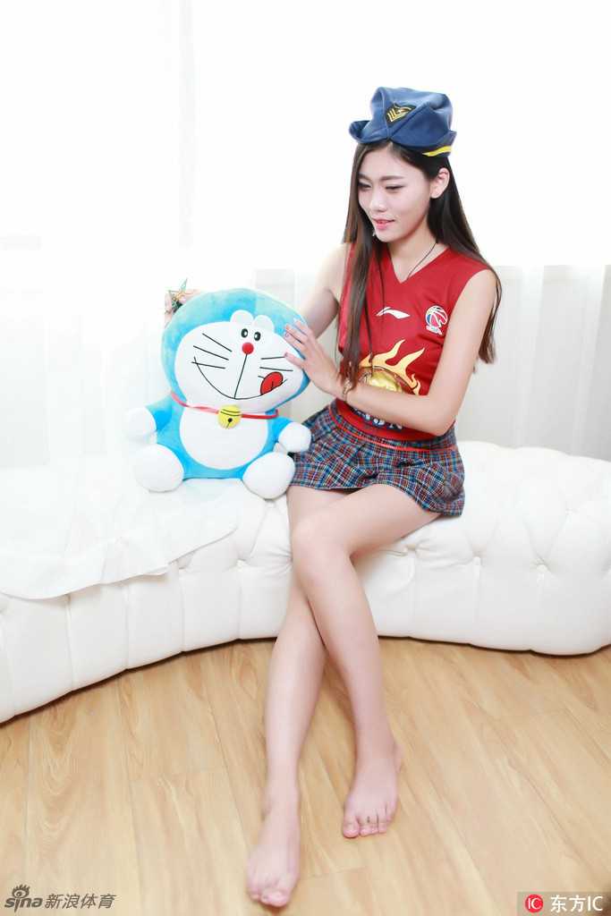 她双手高举玩偶挡在眼前，只露出一双会说话的眼睛，纤细的手臂和白皙的长腿在阳光下闪闪发光