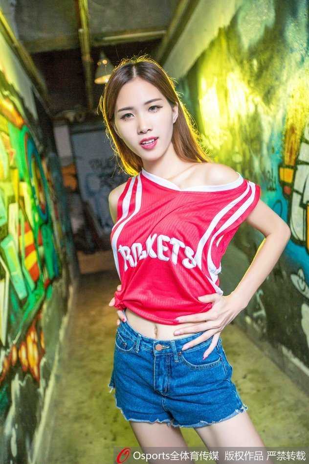 这位忠实的火箭女球迷在场边高举手机，想要记录下赛场的每一个精彩瞬间。她的侧颜精致，马尾辫显得活力十足，紧身T恤勾勒出她完美的身材曲线，此刻她不仅是看客，更是这个篮球故事的一部分。