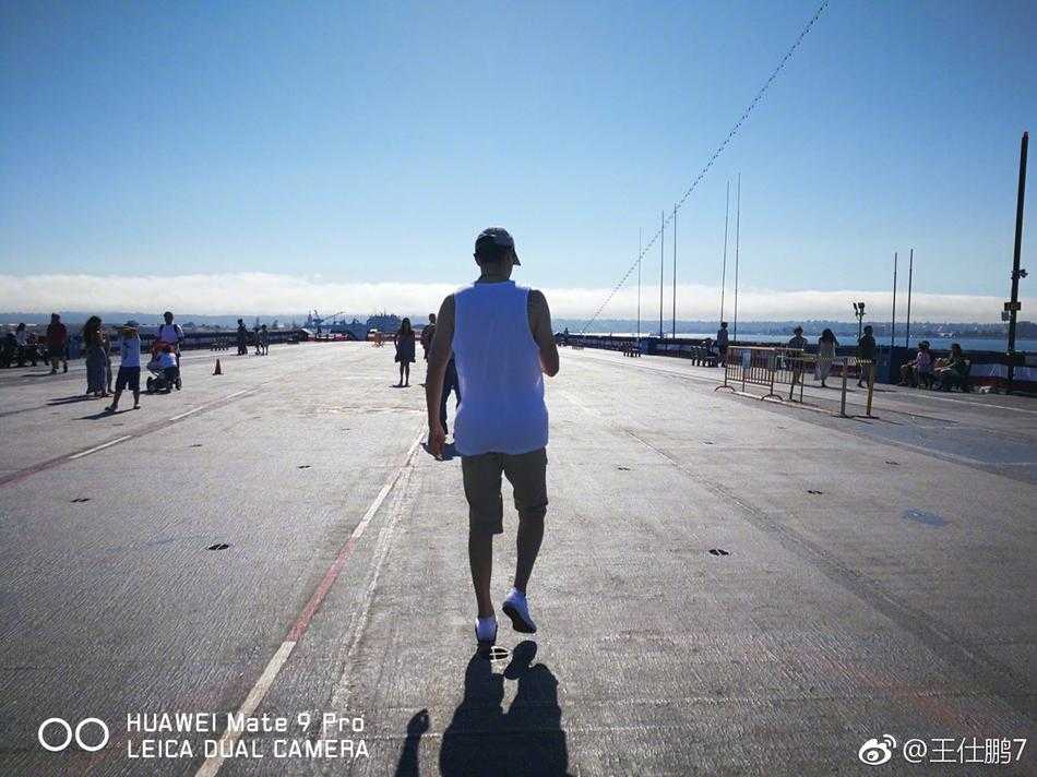 巴尔博亚公园的标志性钟楼在午后的阳光下显得庄重而优雅，王仕鹏站在西班牙殖民复兴风格的拱门走廊下，抬头仰望精美的建筑细节。