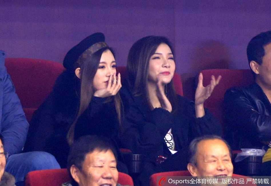 镜头拉近，睢冉爱妻微微侧身与身旁友人交谈，脸上浮现出淡淡的微笑。背景是模糊的球场灯光和攒动的人头，但那份属于球员家属的从容与骄傲，却在人群中清晰可辨。