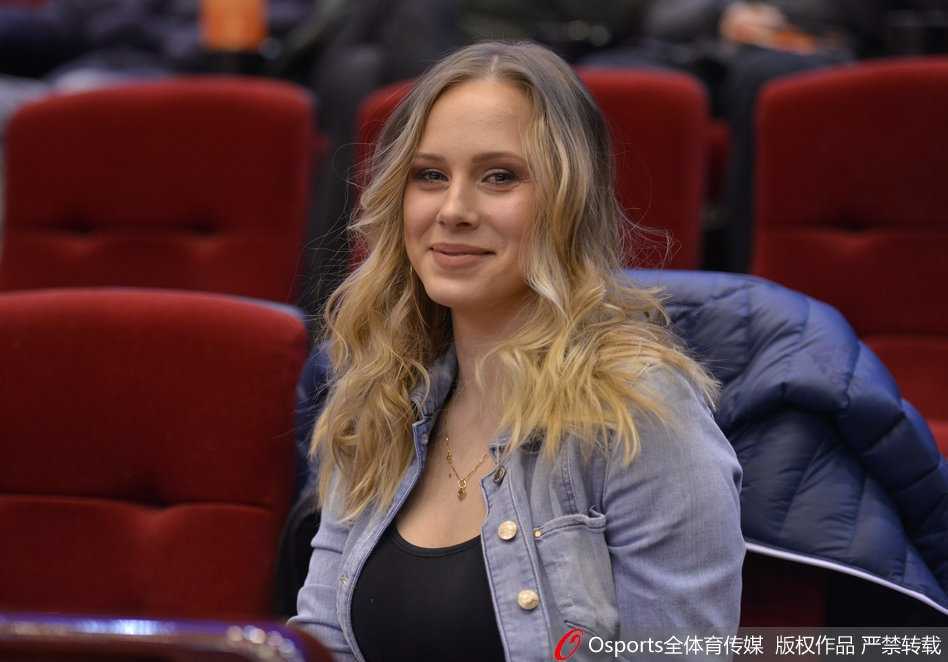 当丈夫在场上奋力拼杀时，她安静地坐在家属区，双手轻握福字置于膝上，目光越过人群深情地望向场内，嘴角那一抹弧度里，藏着只有枕边人才懂的鼓励与柔情。