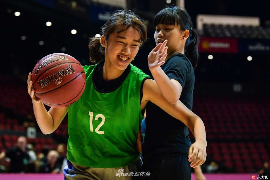 身穿红色球衣的小球员在职业赛场上毫不怯场，他正眼神坚毅地运球突破，对面的大哥哥则面带微笑认真防守，传承在这一刻悄然发生。