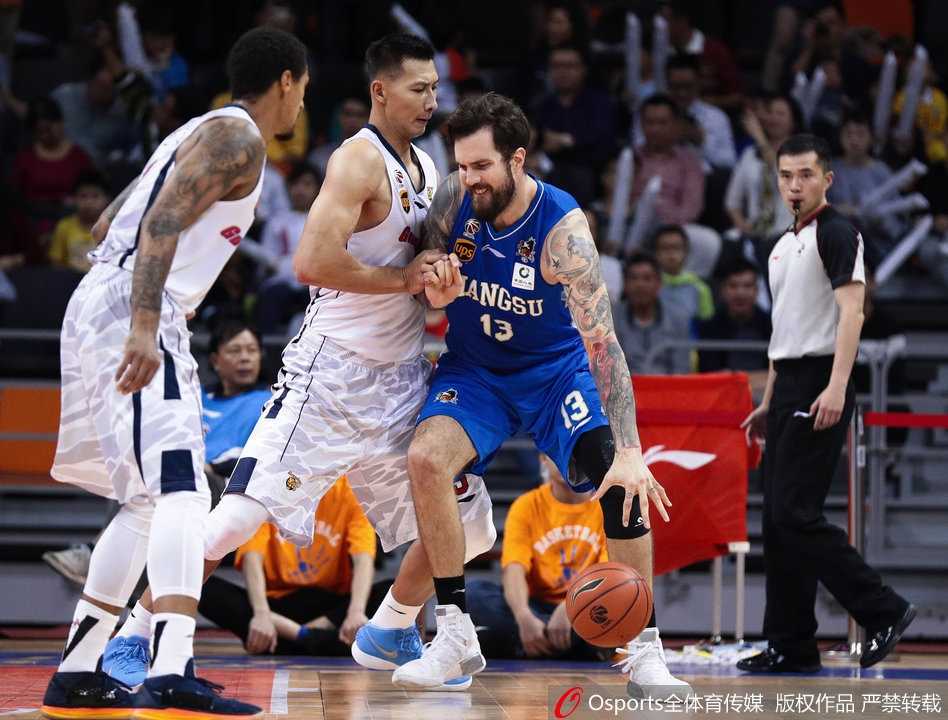 易建联叉腰低头站在篮下，眼神中充满不甘，身后是欢庆胜利的江苏球员，巨大的反差让人感受到竞技体育的残酷。