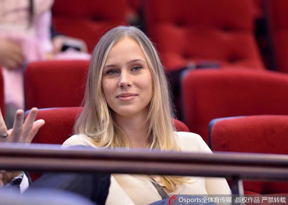 她似乎在为场上的某个精彩回合振臂高呼，嘴角洋溢着灿烂的笑容，精致的侧颜在球场灯光的映照下显得格外迷人。