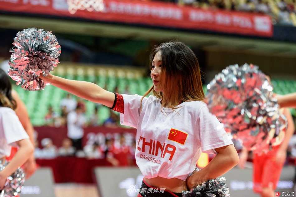 镜头聚焦于一位笑容甜美的啦啦队员，她手持闪亮的花球，眼神充满自信，身后的队友虚化成光影，仿佛整个舞台都为她闪耀。