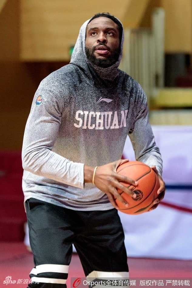 蜀道难·巨人擎天:哈达迪热饮暖身引领四川金强寒夜逆袭 哈达迪在进行拉伸训练,表情略显疲惫但眼神坚毅,手中的热饮在寒冷的球馆里升起袅袅白气。