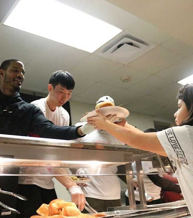 融入·感恩:周琦与哈登阿里扎的休城温情时刻 周琦与阿里扎并肩站在厨房的操作台前,身前摆放着金黄色的烤火鸡,两人面对镜头,眼神中透露出对即将到来的节日大餐的期待。