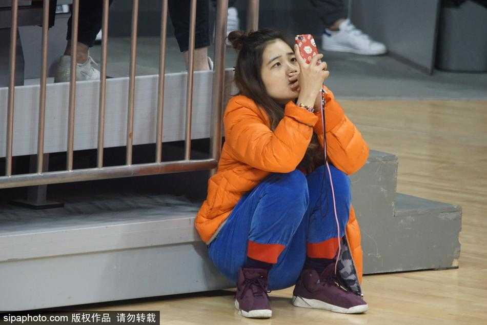 这位美女观众在人群中微微侧头，嘴角带着一丝若有若无的微笑，仿佛是看到了场上某个有趣的回合，这种自然的瞬间流露，比刻意摆拍更显动人。