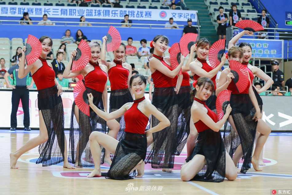 两位宝贝正在场边交流舞步，她们赤足站立，专注的神情与白皙的双腿形成鲜明对比，展现了篮球宝贝在舞台下的另一面，专注而又不失柔美。