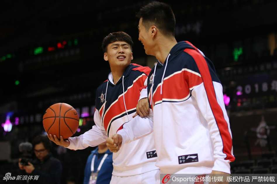 训练场上赵睿从两位队友中间探头张望，脸上挂着狡黠的笑容，仿佛在偷听战术又像在寻找恶作剧的目标。