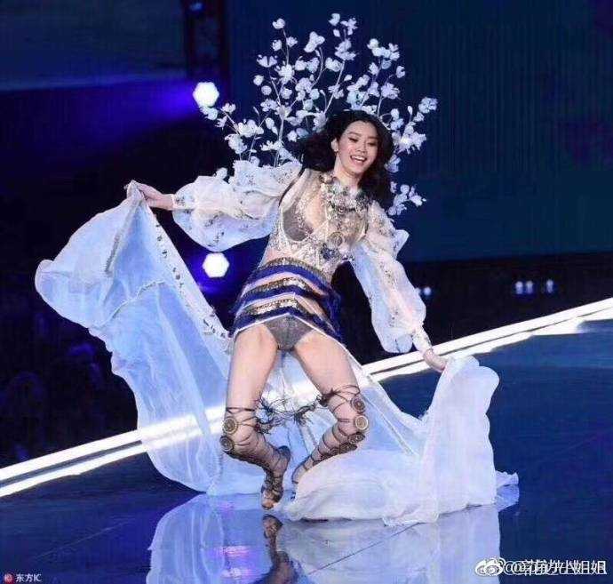 身披轻盈薄纱的奚梦瑶在闪耀的维密舞台上不慎被裙摆绊倒，双膝触地，一瞬间的错愕写在脸上