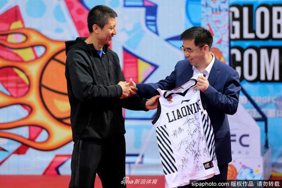 热情的沈阳球迷将郭士强团团围住，纷纷举起手中的球衣和篮球索要签名，郭士强低头认真为球迷签名。