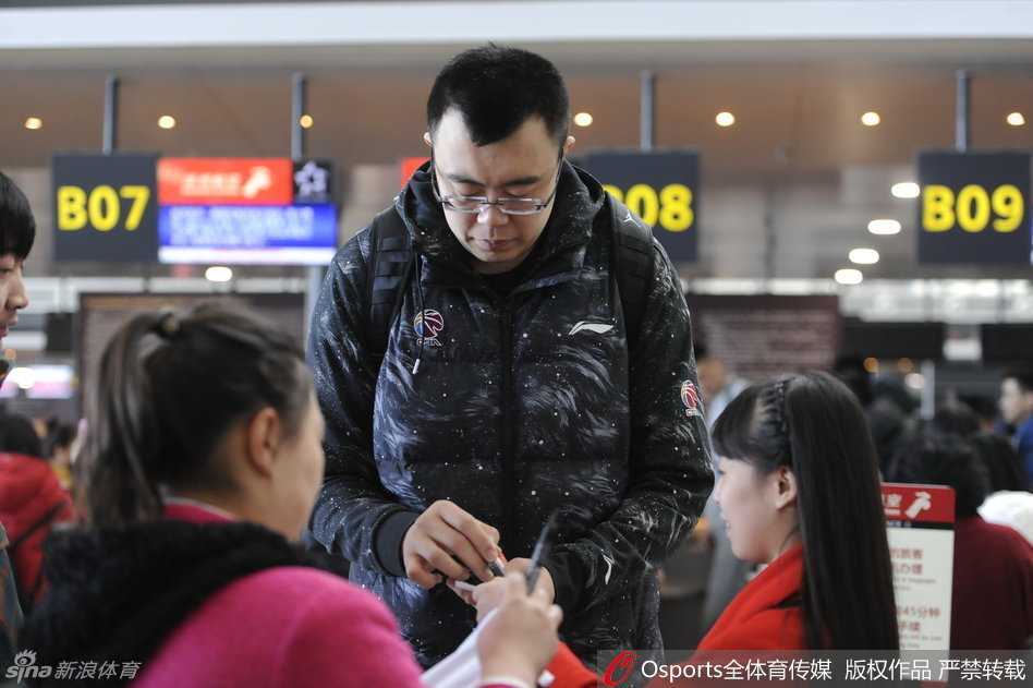 韩德君弯下巨大的身躯，将耳朵凑近一位坐着轮椅的老奶奶，耐心听她说话，手中的笔一直悬停在照片上等待签名