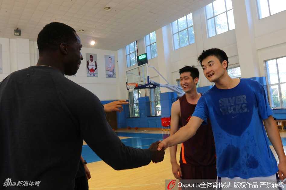 巴斯在训练馆内饶有兴致地观看着墙上教练和队友的照片，墙上按照球衣号码排列的巨幅照片吸引了他的目光。