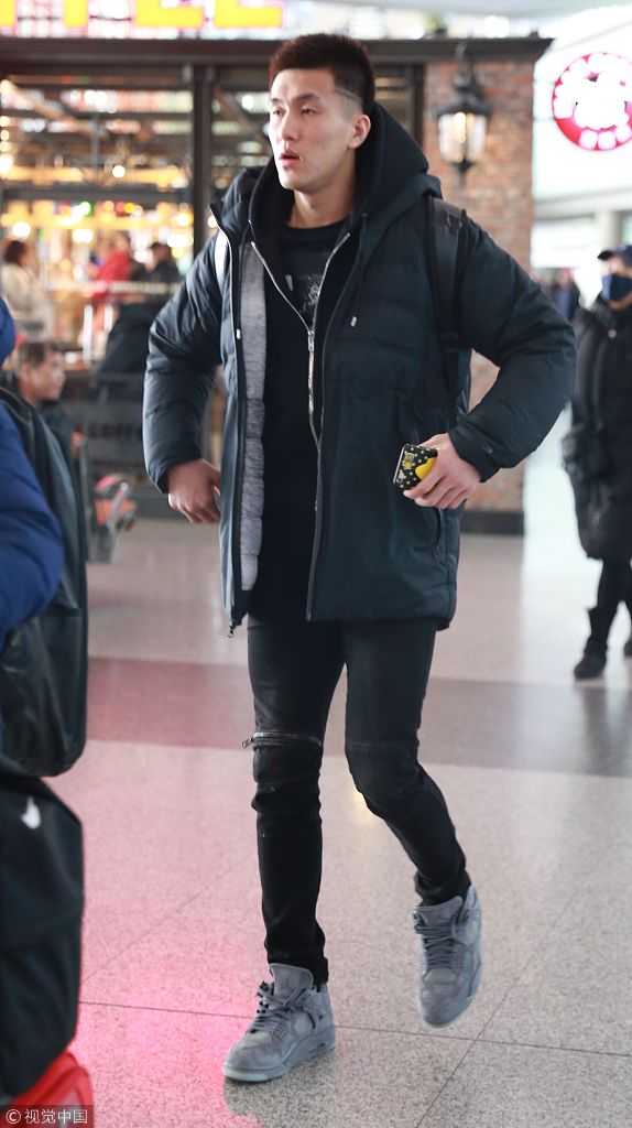 郭艾伦微弓着背，低垂着眼帘，手中握着笔在球迷的卡片上认真划过，身后的机场告示牌虚化成影，疲惫与温柔在这一刻交融