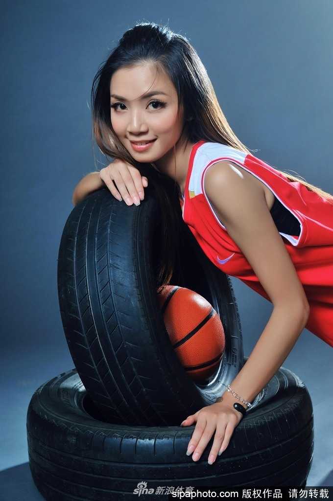 钟苑庄坐在篮球上，双腿自然前伸，明媚笑容与球场木地板的暖色调相得益彰