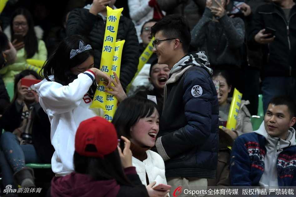 在四川队主场明亮的聚光灯下，一位勇敢的四川男球迷在全场上万名观众的注视下，缓缓单膝跪地，向他心爱的女孩伸出握着戒指的手，眼神中满是期待与真挚。