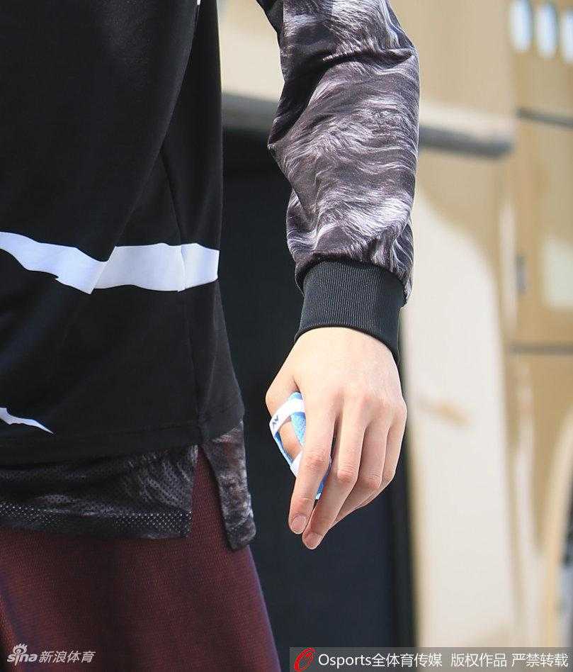 李根手提篮球鞋，大步流星地走在通往训练馆的通道上，眼神坚定，展现出总决赛关键先生的气场与自信。