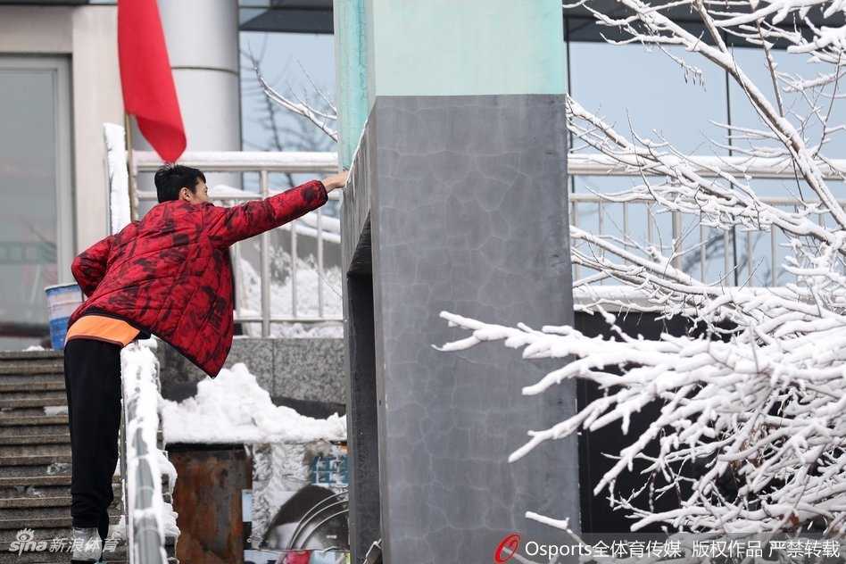 胡金秋在乌鲁木齐雪景中身穿广厦队外套，目光深邃地望向远方，仿佛在思考即将到来的激烈对决。