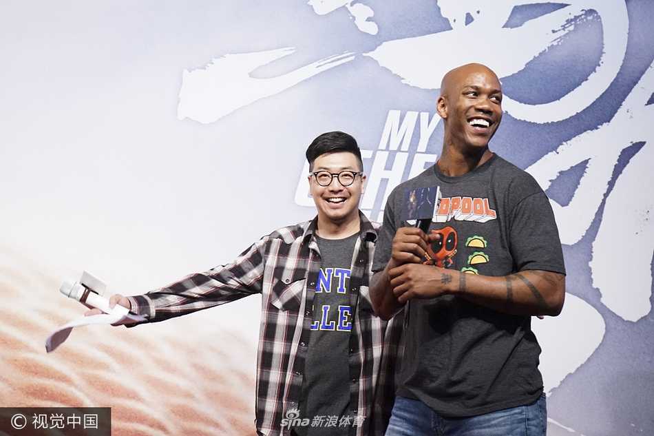 马布里手持麦克风，神情投入，似乎在讲述一个关于爱与梦想的故事。背景板上的电影海报揭示着这位“纽约客”在北京的第二故乡情缘，他的每一个手势都充满了力量感。