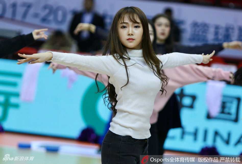 一位山东啦啦队队员在赛前热身时回眸，额头渗出细密汗珠，专注的神情中带着一丝俏皮，仿佛在嗔怪镜头的打扰。