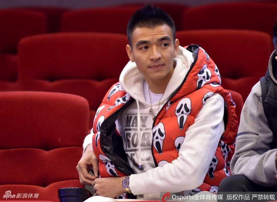 齐鲁冬夜篮球盛宴,看台星光熠熠耀全场 看台座位上,一位穿着时尚白色外套的年轻女球迷,手持橙色加油棒,侧身与同伴交谈,脸上洋溢着灿烂的笑容,仿佛对山东队的表现十分满意。