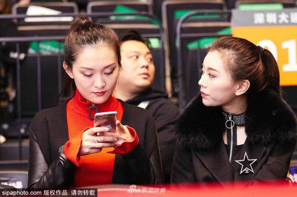 比赛中场休息时，丁彦雨航女友安静地坐在座位上，眼神望向远处正在热身的球员区域，手中拿着一瓶水，似乎随时准备着为走下赛场的心上人递上一份清凉。